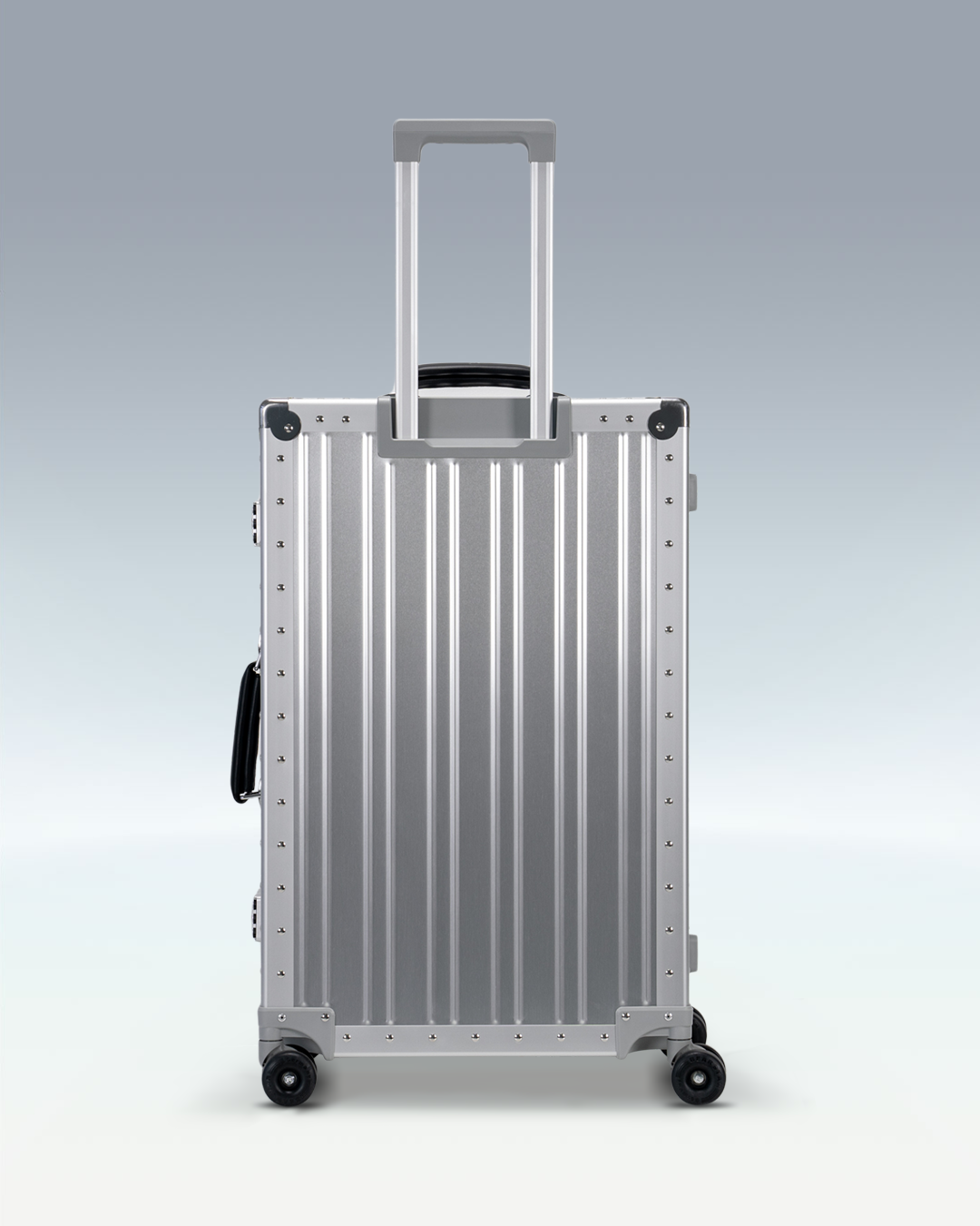 Portar Lucent aluminum checked luggage in Lunar Silver, back view with the telescoping handle extended