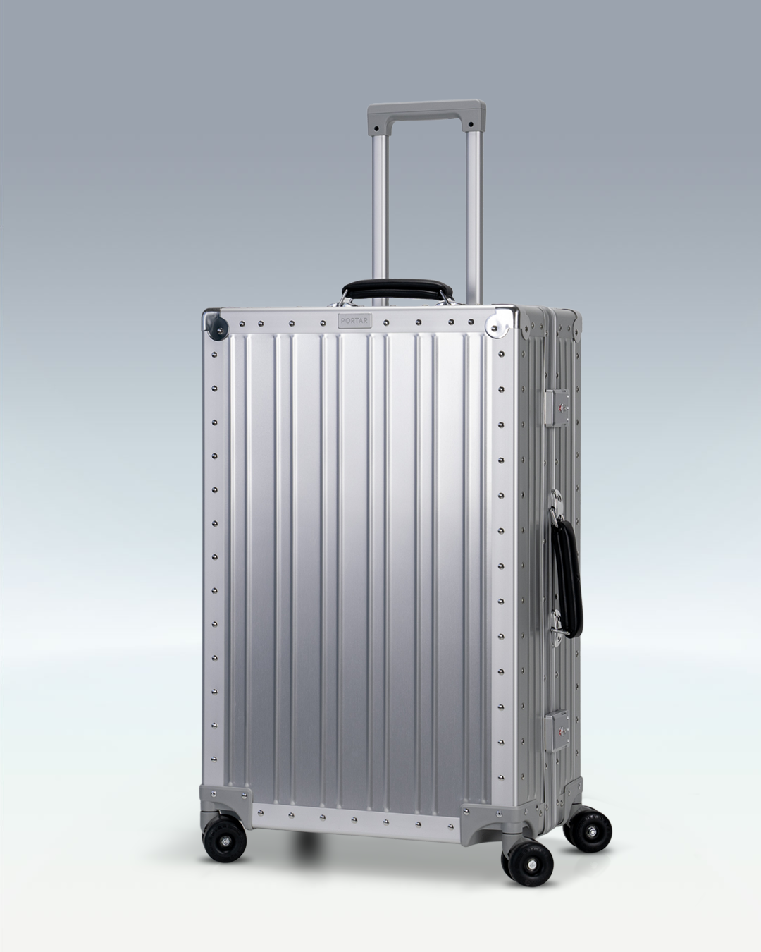 Portar Lucent aluminum checked luggage in Lunar Silver, three-quarter view with the telescoping handle extended