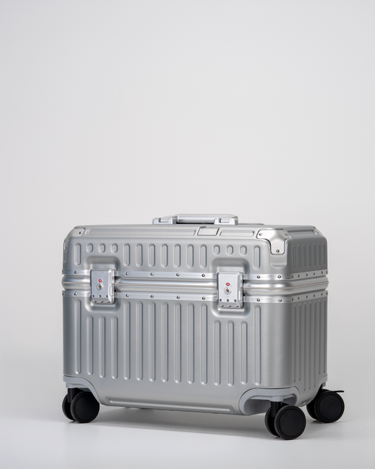Silver pilot suitcase with wheels on a light gray background