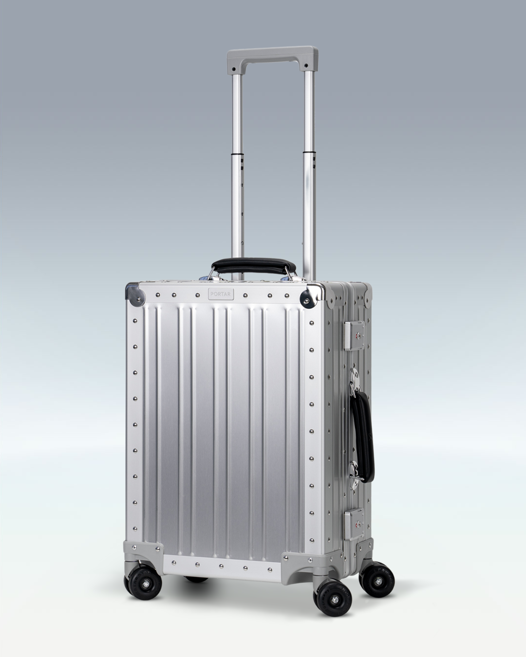 Portar Lucent aluminum carry-on luggage in Lunar Silver, three-quarter view with the telescoping handle extended