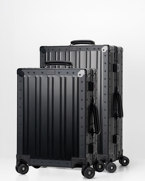 Two Portar Jet Black Aluminum suitcases with black handles bundled as a travel set on a light gray background