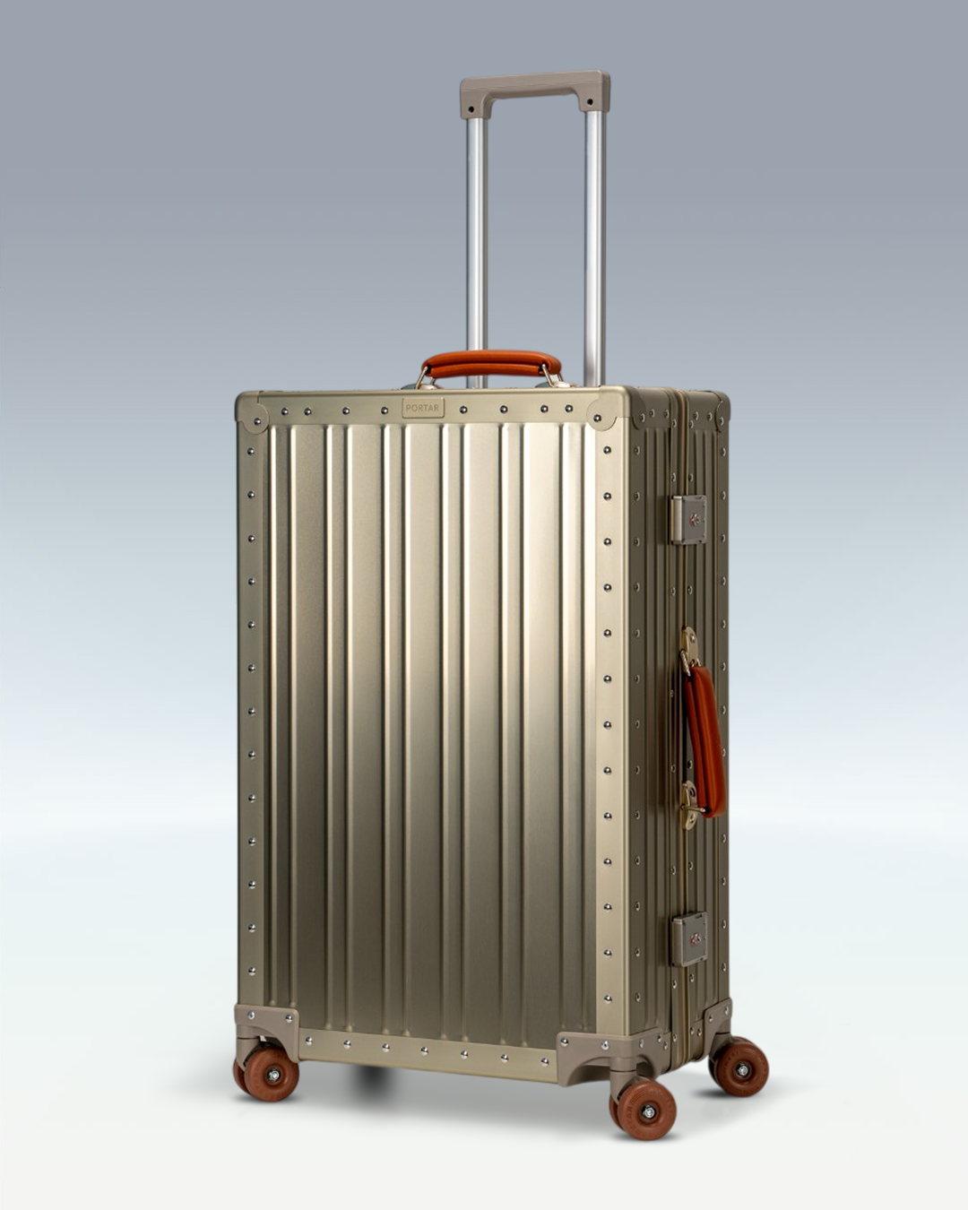 Portar Lucent aluminum checked luggage in Champagne Gold, three-quarter view with the telescoping handle extended