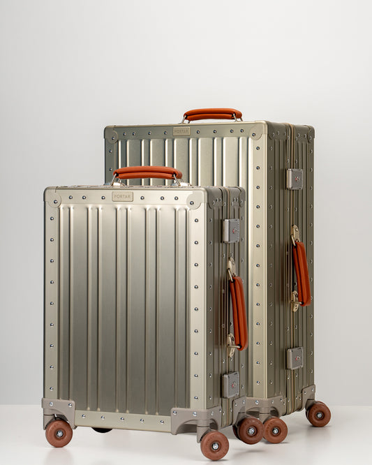 Two Portar Champagne Gold Aluminum suitcases with brown handles bundled as a travel set on a light gray background