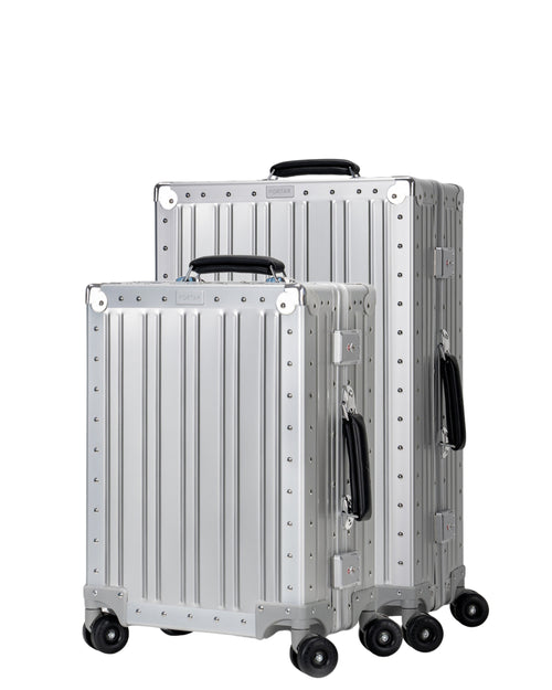 Two Portar Lunar Silver Aluminum suitcases with black handles bundled as a travel set on a light gray background