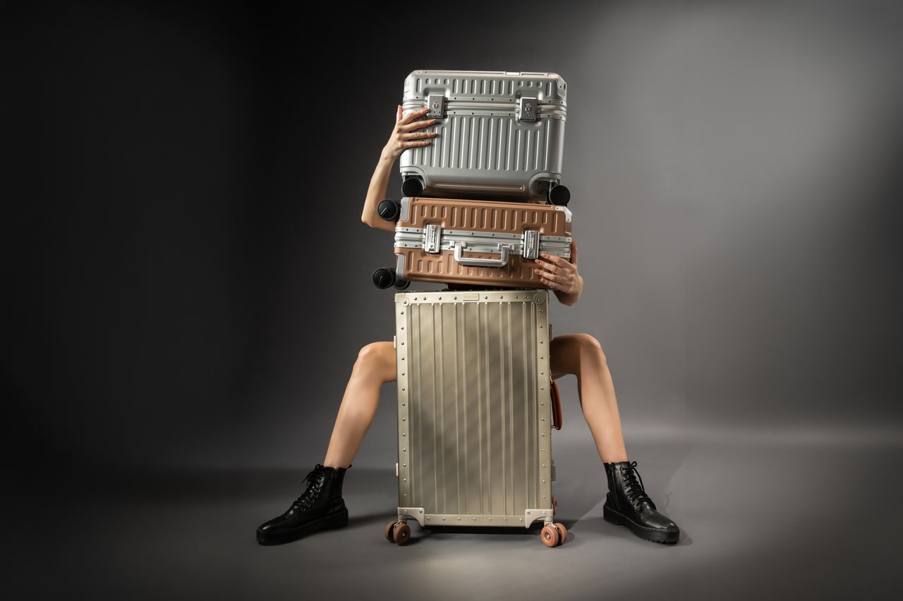 Portar's three collection suitcases stacked vertically with a model behind them