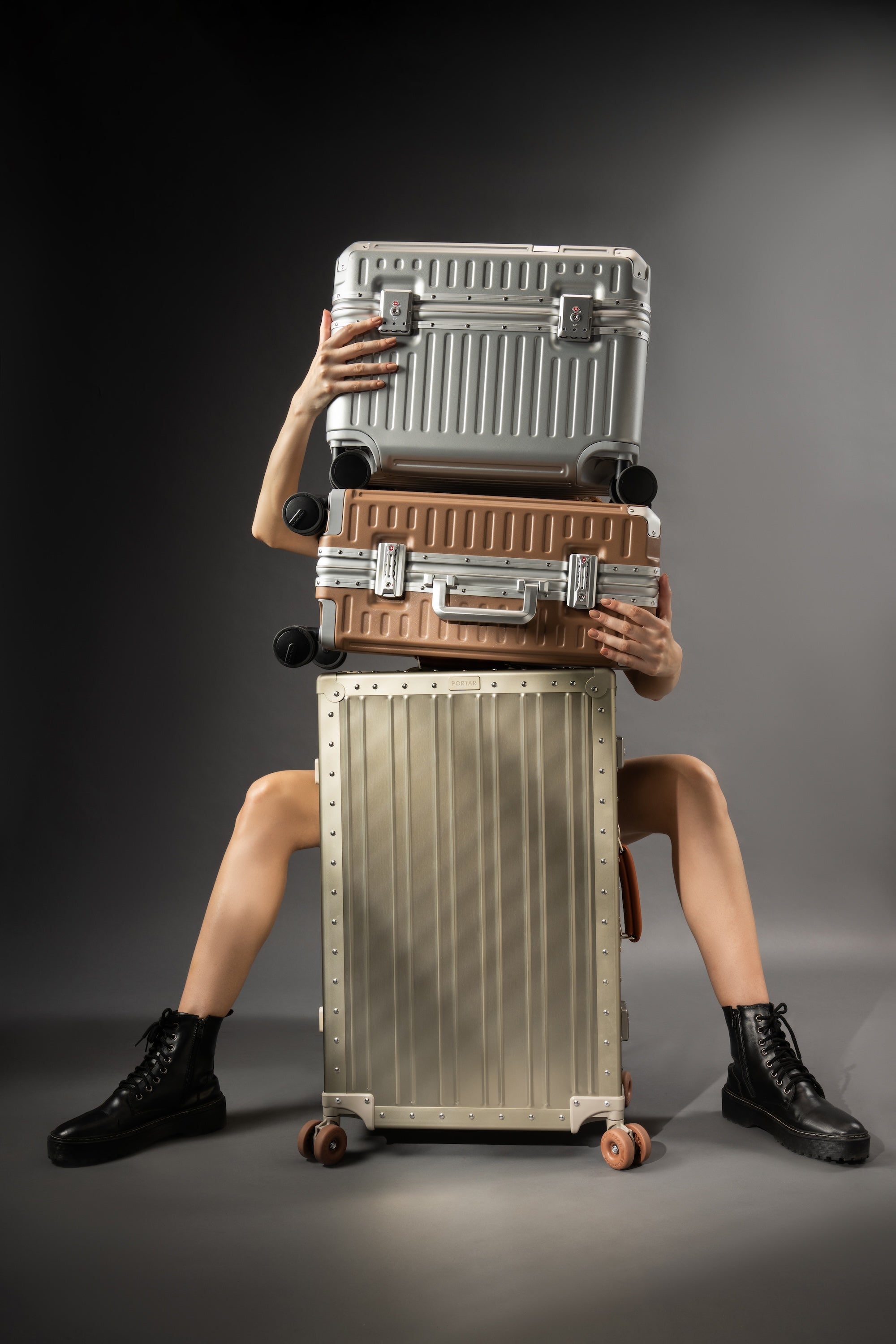 Portar's three collection suitcases stacked vertically with a model behind them