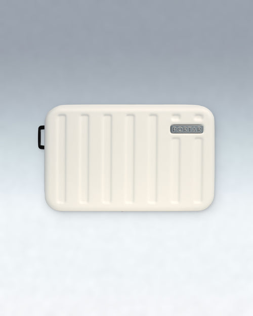 An Cloud Dancer White rectangular hard case with rounded corners, vertical ribbed indentations, a small black loop on the left side, and a gray 'PORTAR' logo badge on the top right, shown against a light gray gradient background.