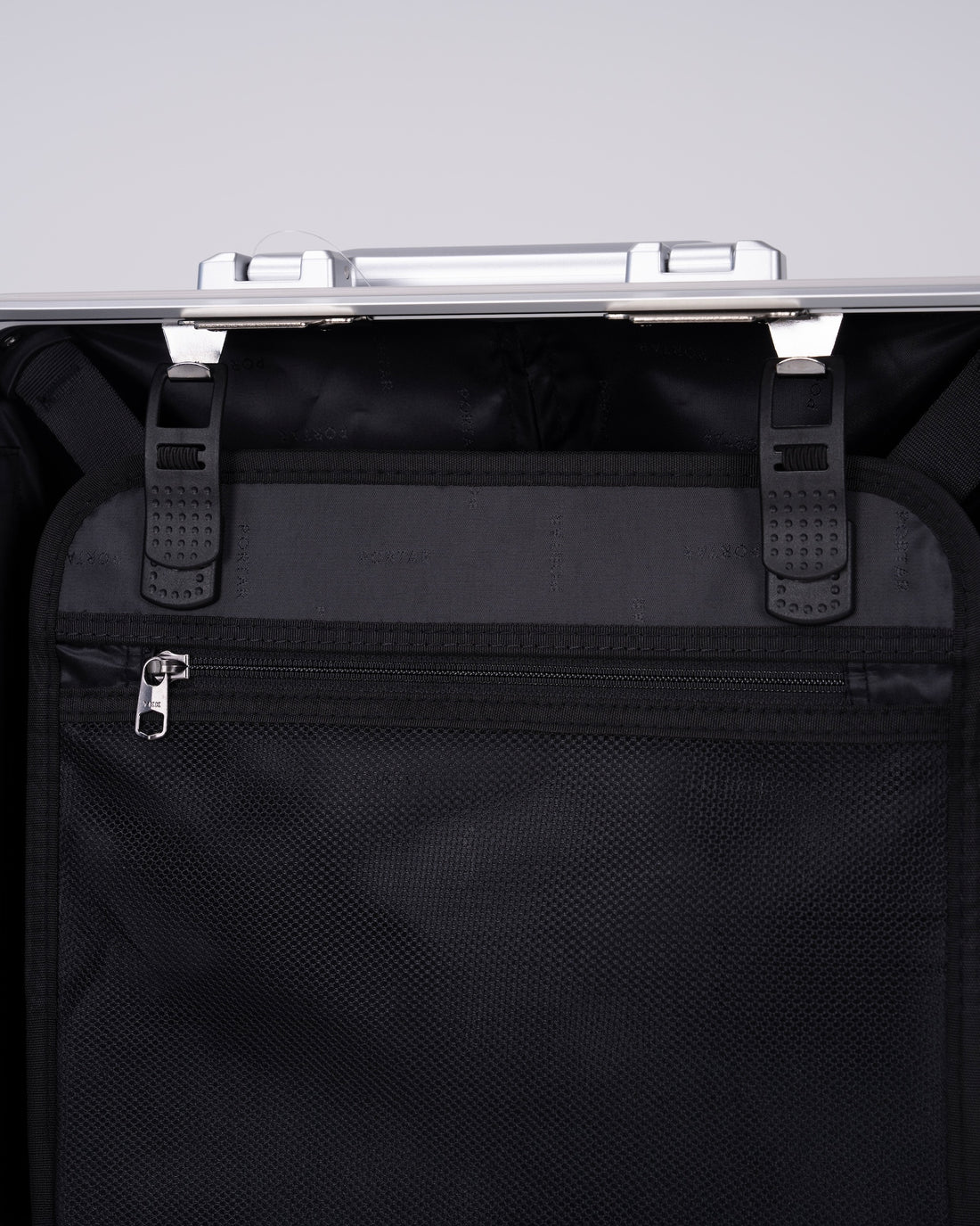 Portar polycarbonate shell with aluminum EdgeFrame suitcase interior details with black interior on one side of the suitcase on a light gray background