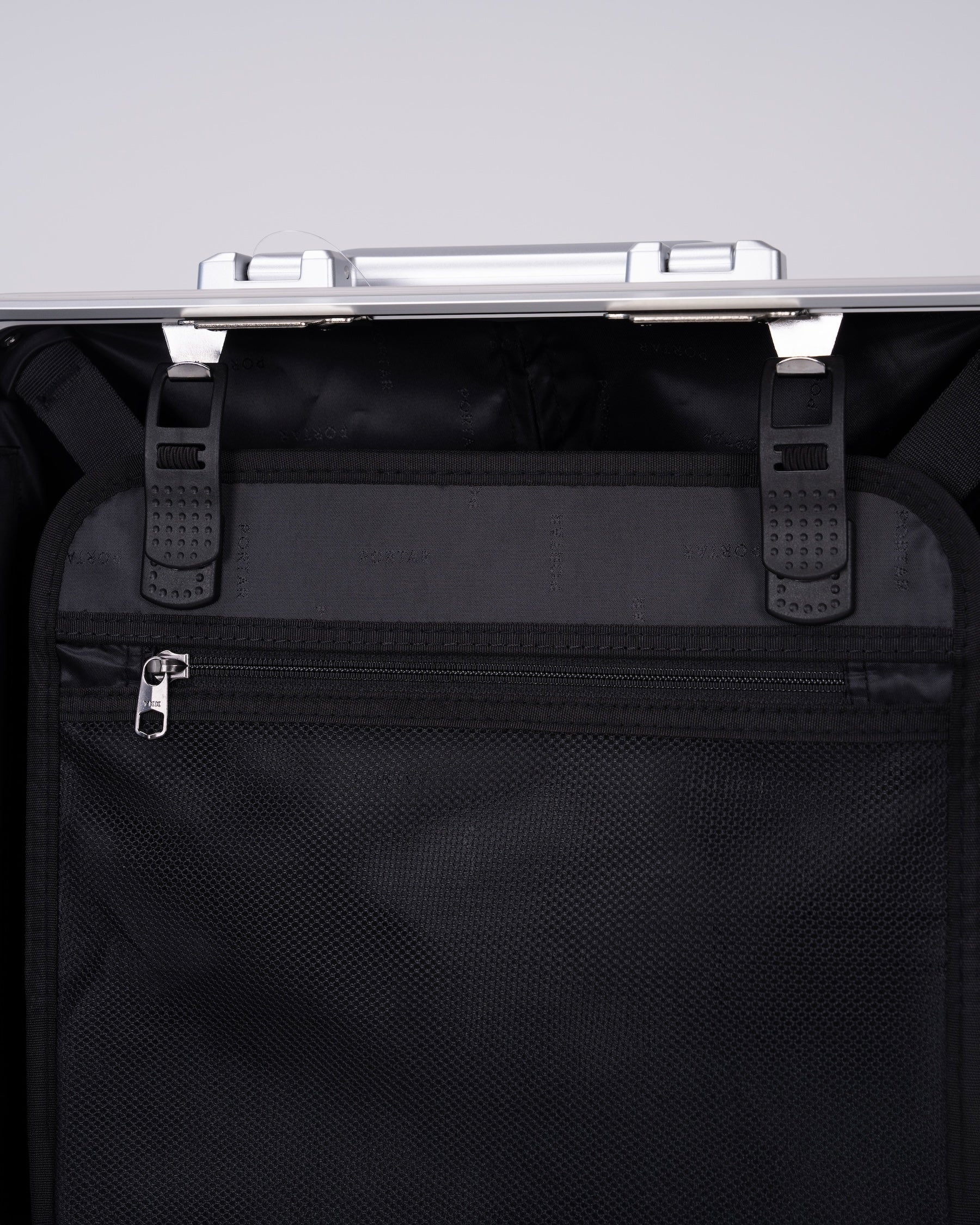 Portar polycarbonate shell with aluminum EdgeFrame suitcase interior details with black interior on one side of the suitcase on a light gray background