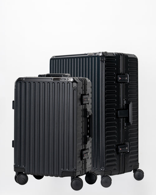Two Portar Jet Black suitcases with black handles bundled as a travel set on a light gray background