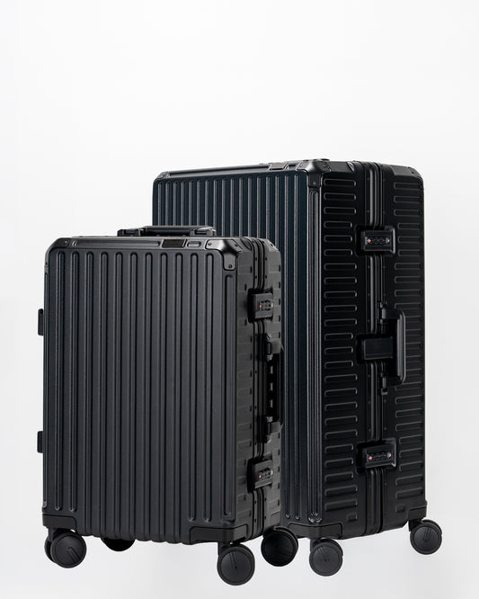 Two Portar Jet Black suitcases with black handles bundled as a travel set on a light gray background