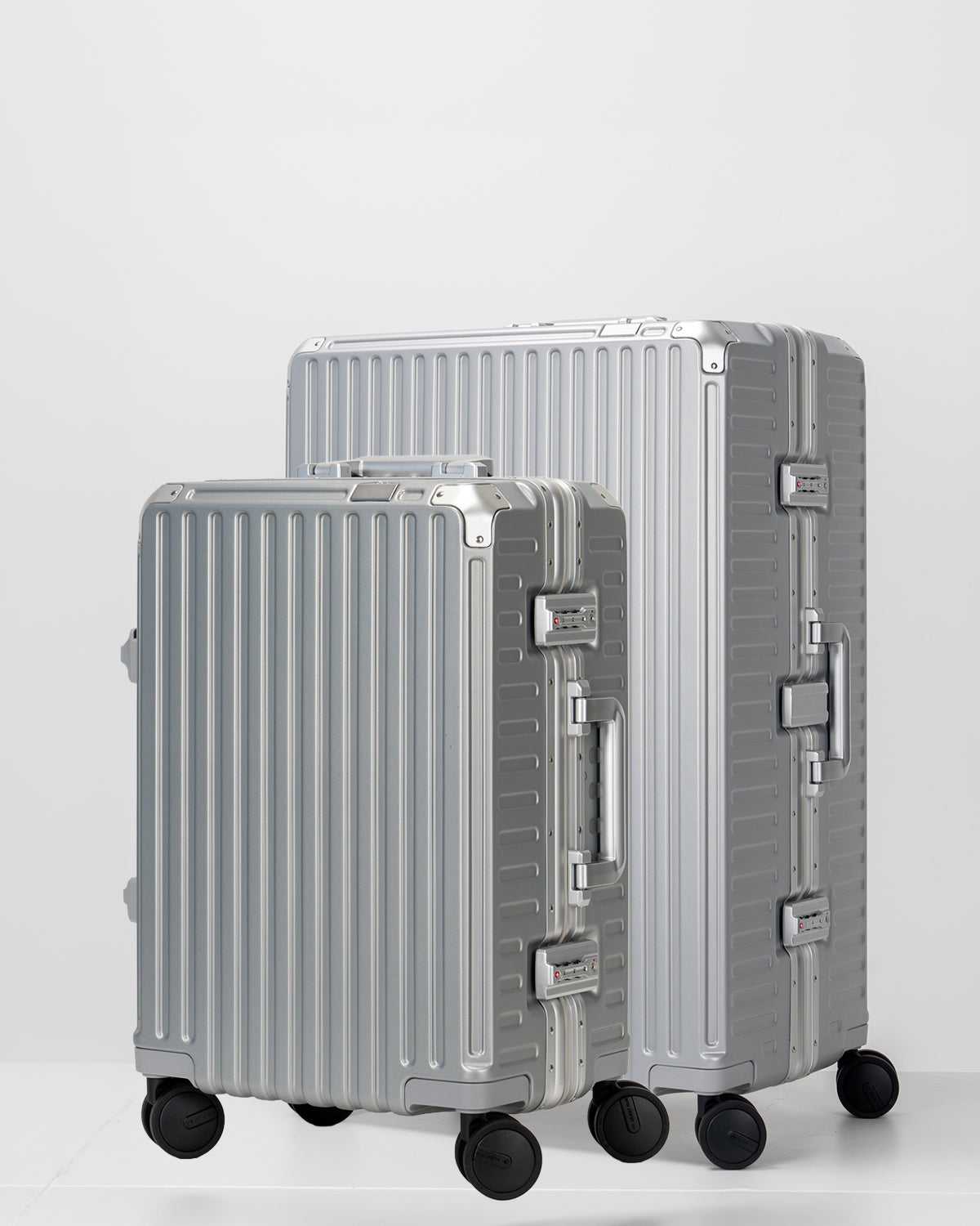 Two Portar lunar silver suitcases with silver handles bundled as a travel set on a light gray background