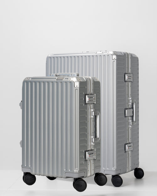 Two Portar lunar silver suitcases with silver handles bundled as a travel set on a light gray background