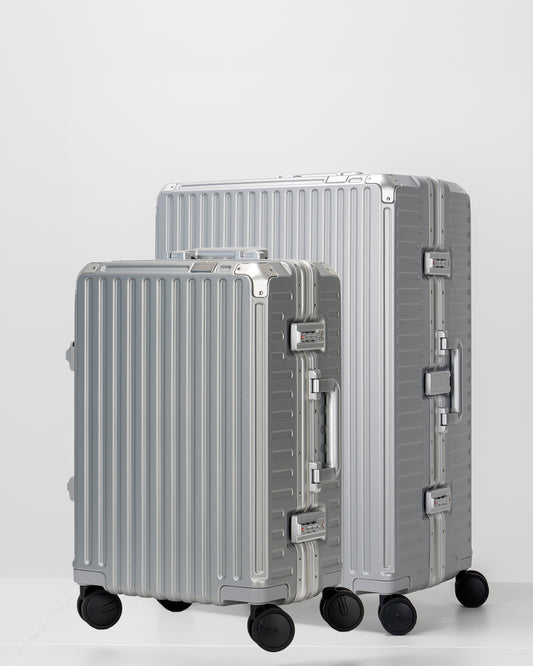 Two Portar lunar silver suitcases with silver handles bundled as a travel set on a light gray background