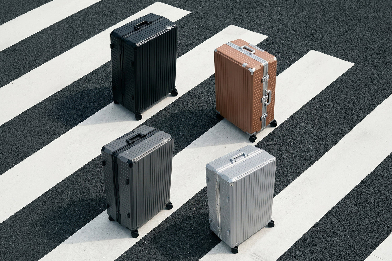 Four Portar Valence polycarbonate shell with aluminum edgeframe suitcases of different colors on a black and white striped surface